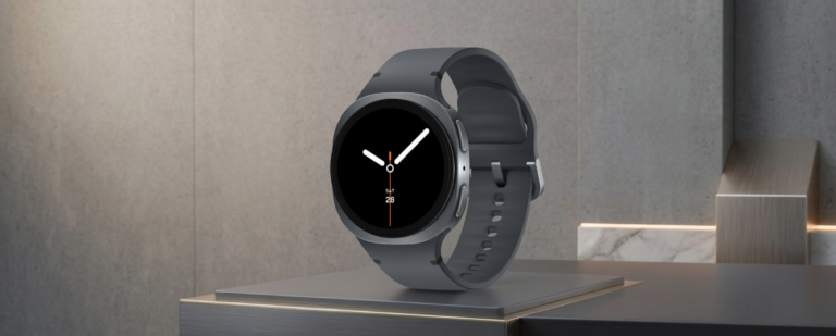 Samsung Galaxy Watch 8 sa tamnosivom narukvicom postavljen na moderno mat postolje ispred minimalističkog betonskog zida